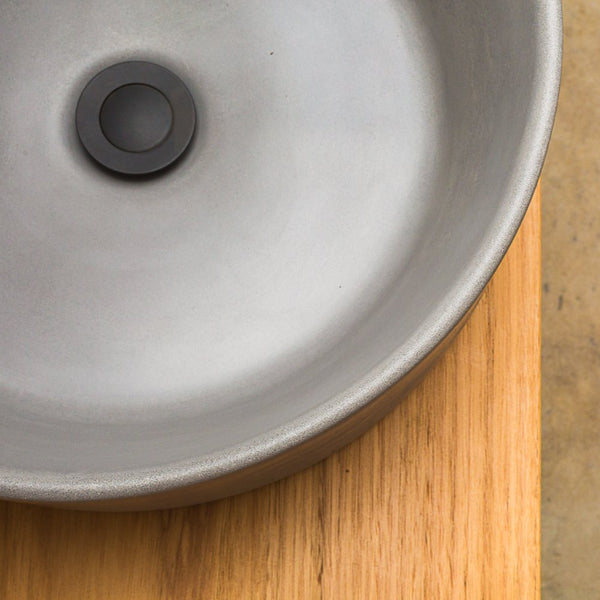Dark grey concrete basin on timber. Hand made round concrete basin is the perfect match to a timber vanity.